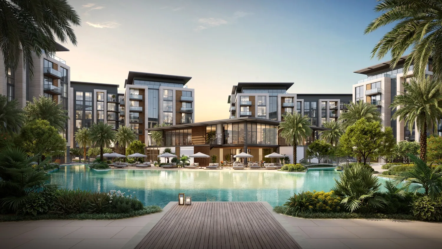 Landscaped resort pool and clubhouse framed by mid-rise apartment buildings at dusk in Dubai Land Residence Complex